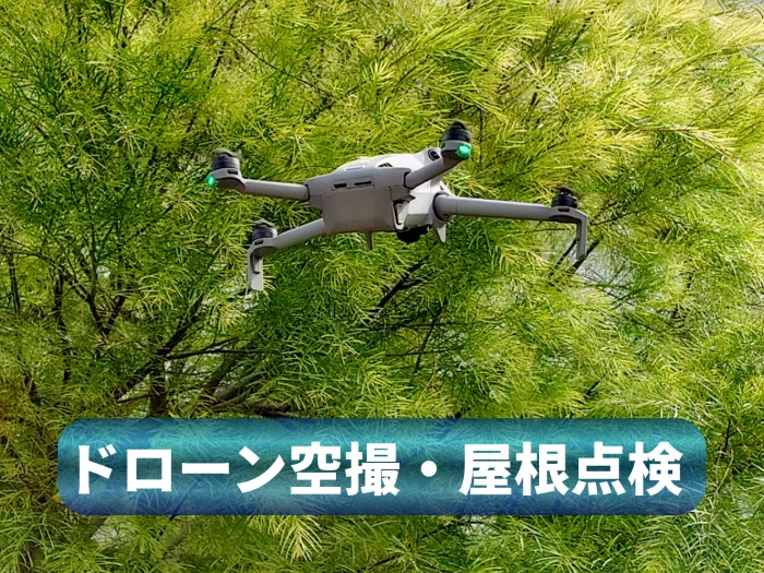 青空の下、樹木の上空を飛行する不動産・建築向け空撮用ドローン