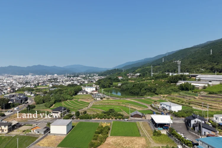 ドローンで上空から撮影した市街地と田園風景、周辺の山並みを見渡す空撮写真