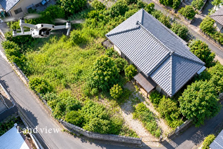 空き家の敷地全体をドローンで上空から撮影し、雑草や庭木の繁茂状況を確認するイメージ