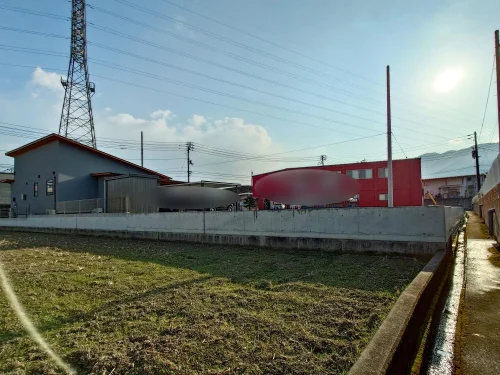 四国中央市上柏町10-8 売土地 敷地内から見た擁壁と周辺建物および電線の状況